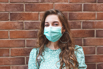 Woman wearing face mask against brick wall during COVID-19 outbreak