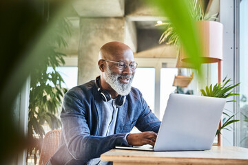 Smiling mature businessman working from home on laptop