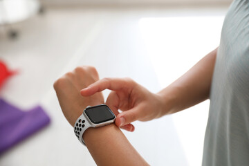 Woman checking fitness tracker in gym, closeup