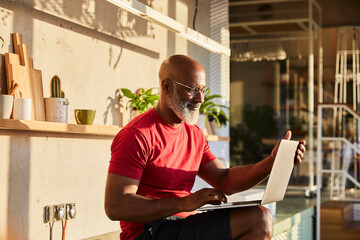 Smiling businessman concentrating on work while using laptop at home