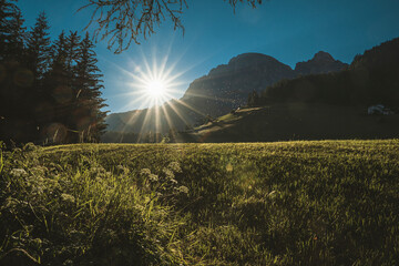 Italy, South Tyrol, Corvara, Sun setting over meadow in Dolomites