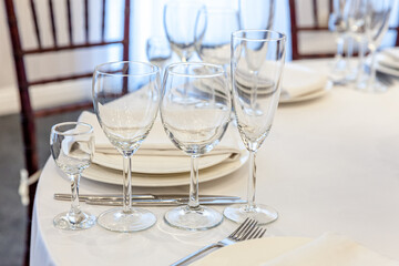 Fancy table set for dinner with napkin glasses in restaurant, luxury interior background. Wedding elegant banquet decoration and items for food arranged by catering service on white tablecloth table.