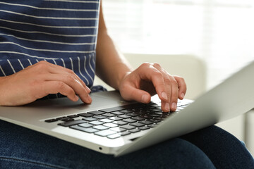 Young woman using laptop for search indoors, closeup