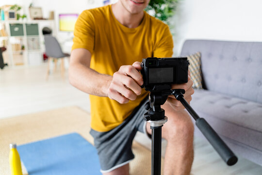 Young man adjusting video camera while sitting at home