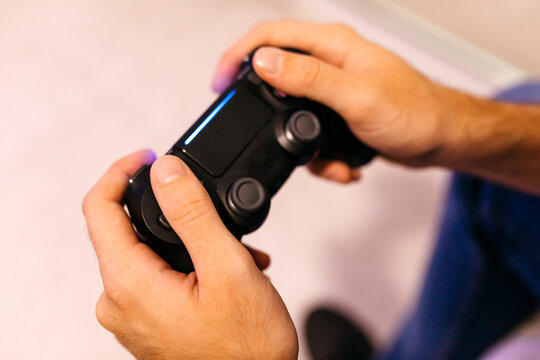 Hands of young man holding controller while playing video game at home
