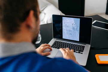 Adult male student doing mathematics homework through laptop at home