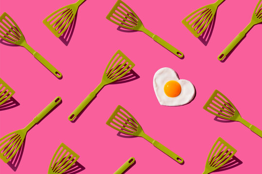 Pattern of green spatulas with single heart shaped fried egg