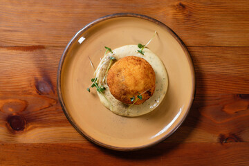 Meat baked in rice with mashed potatoes, garnished with herbs on a clay plate.