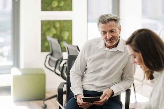 Smiling businessman looking at businesswoman working at office - Powered by Adobe