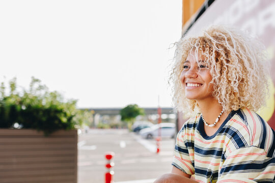 Smiling blond curly haired woman looking away