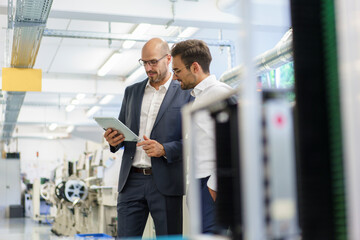 Businessmen discussing over digital tablet while standing at factory