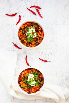 Two bowls of vegetarian stew with red lentils, chili peppers, celery, kidney beans, tomatoes, carrots and sour cream