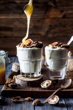 Two glasses of Greek yogurt with honey, figs and walnuts