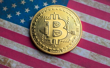 Golden bitcoin coin on top of United States Flag.