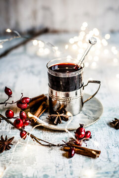 Christmas lights, rose hips and cup of mulled wine with cinnamon sticks and star anise
