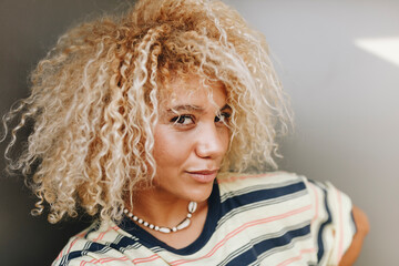 Confident woman with blond curly hair taking selfie against metallic wall