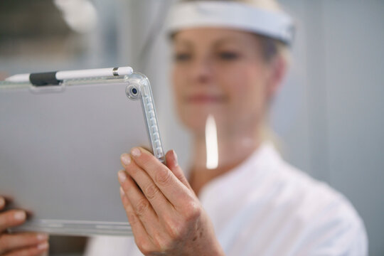 Close-up of female scientist wearing protective face shield while using digital tablet at laboratory