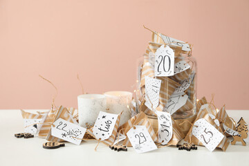 Christmas advent calendar with small gifts and burning candles on white table