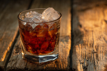 Glass of old whiskey with ice cubes on wooden background. Concept of alcoholic drinks. Advertising and promotion. Bar menu.