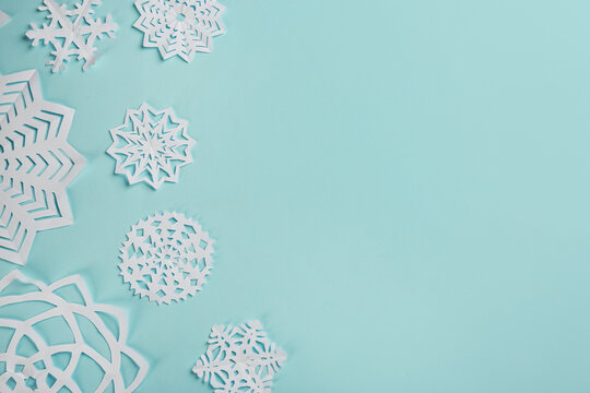 Flat lay composition with paper snowflakes on cyan background. Space for text - Powered by Adobe