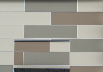 Mosaic like wall siding on a strip mall with large brown, beige, gray rectangles forming a decorative pattern