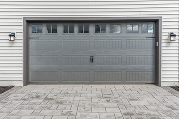 Gray two single car garage door framed with architectural stone to add accent, with transom light windows divided by muntins grills 