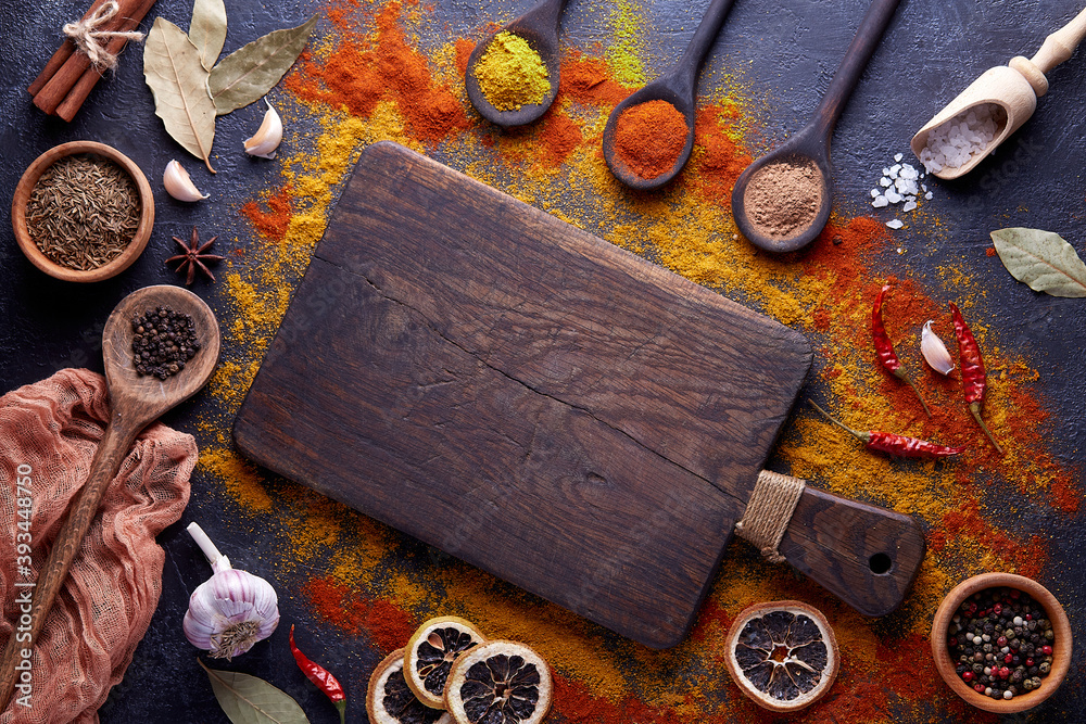 Wall mural cutting board with spices and herbs for cooking meat on dark background