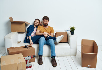 Fototapeta na wymiar man and woman on the couch moving boxes renovation work leisure interior room