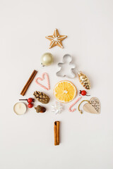 Fototapeta na wymiar Christmas, winter, new year composition. Creative fir tree made of pine cone, cinnamon sticks, dried oranges, gingerbread on white background. Flat lay, top view, copy space
