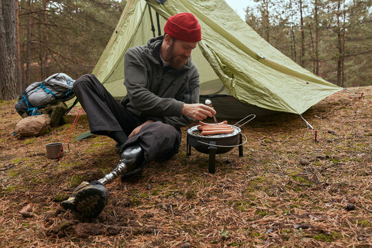 Disabled Traveller Grilling Sausages On Portable Roaster - Powered by Adobe