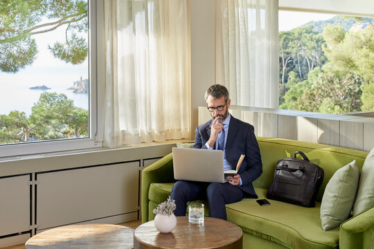 Businessman sitting by the coffee table working on laptop