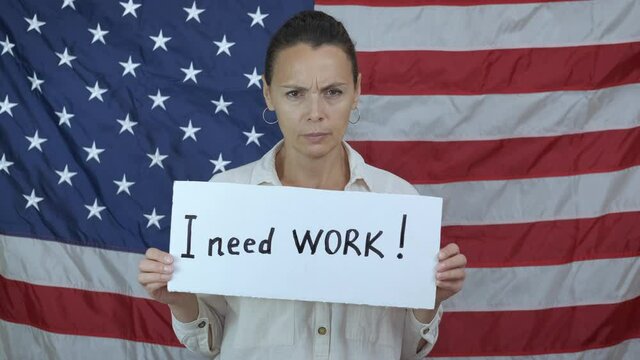 Workless woman. An upset unemployrd woman aasked for word on the background of American flag. A concept of workless time and problems in America.