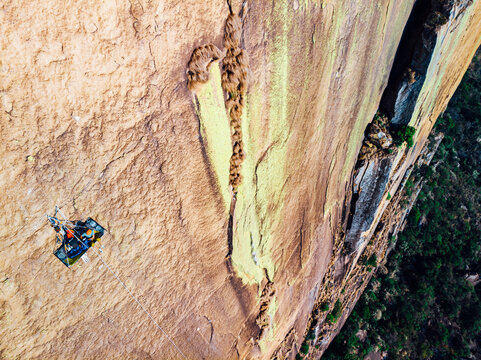 High angle view of rock climber sitting on portaledge in colorful big wall