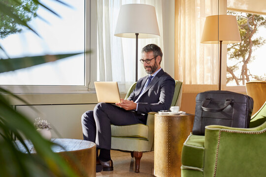 Businessman sitting by the coffee table working on laptop