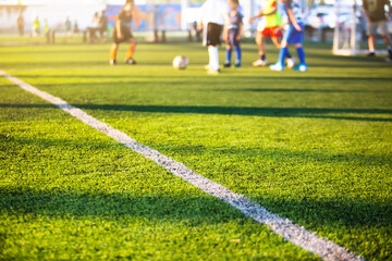 Selective focus to white lines on green artificial grass football fields with kid soccer player....