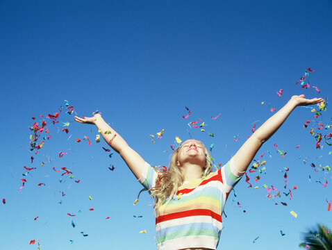 blonde teenage girl in rainbow sweater against bright blue sky