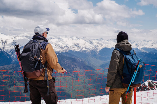 Two adult tourists with backpacks and trekking poles on a mountain top.