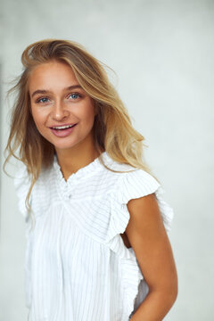 Young blonde woman wearing a blouse and smiling