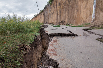 destroyed road consequences of a natural cataclysm of a landslide of soil, crack asphalt paving on...