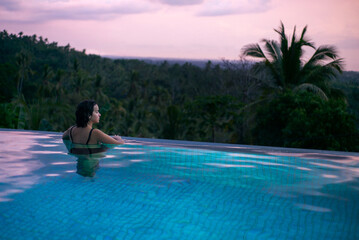 Girl stay at sunset in swimming pool.