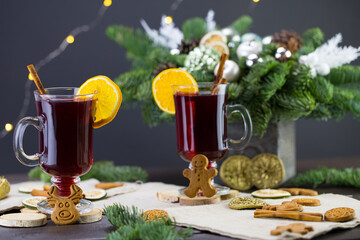 winter treats, a mug of warm wine with an orange, and cookies, ingredients on a wooden brown table. Traditional hot drink for Christmas, in the background Christmas composition