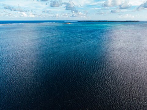 Aerial view of small Guyam Island and Daco Island into clear blue waters on reef