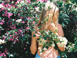 young woman in flowers and nature intertwining with plants