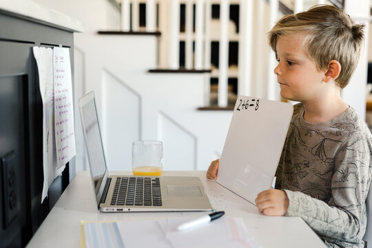 Little boy being homeschooled and doing work online