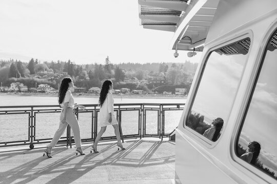 two fashionable women walking across a ferry ship deck