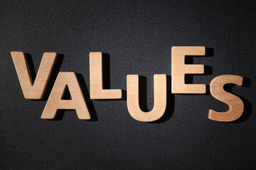 Word VALUES made of wooden letters on black background, flat lay
