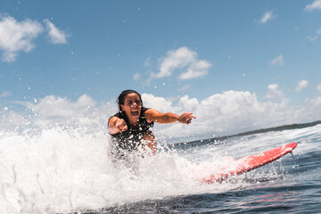 Excited surfer on foamy wave looking at camera on surfboard