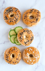 Fresh baked bagels with philadelphia cheese and cucumber on a light table, top view