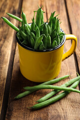 Fresh green beans in mug on wooden table