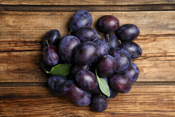 Delicious ripe plums on wooden table, flat lay